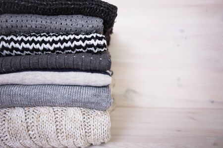 stack of various woolen sweaters on a white wooden backgroundの写真素材