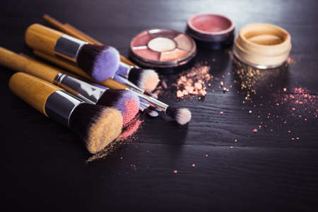 make up brushes with powder and rouge on a black wooden backgroundの写真素材