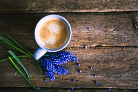 Blue flowers and a cup of coffee on a wooden backgroundの写真素材