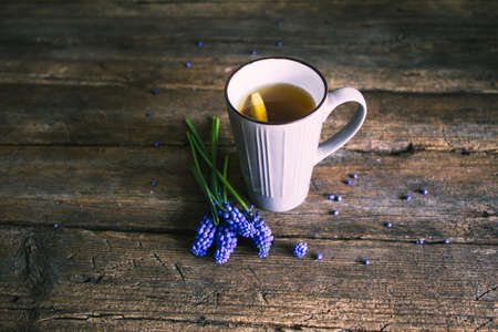 Blue flowers and cup of tea on wooden background. Vintageの写真素材