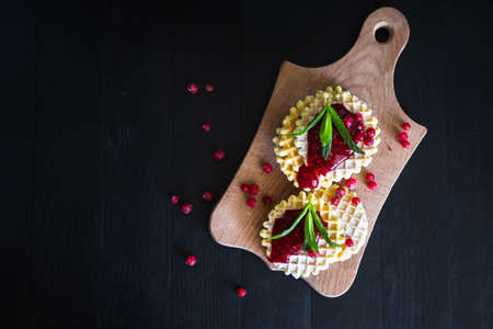 Waffle with berry jam, powdered sugar and mint on black backgroundの写真素材