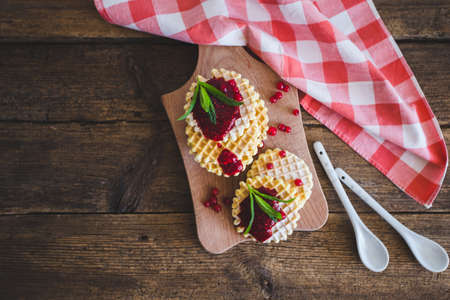 Waffle with berry jam, powdered sugar and mint on black background
