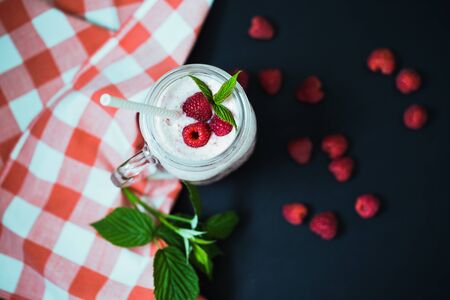 Pink raspberry smoothie in a mason jar with straws on a black backgroundの写真素材