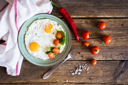 Scrambled eggs with tomatoes on wooden background