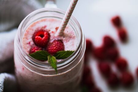 Pink raspberry smoothie in a mason jar with straws