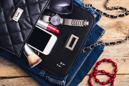 Fashion accessories for a young girl, watch, bracelet, handbag, red lipstick, telephone, brush on a...