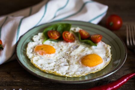 Scrambled eggs with tomatoes on wooden background