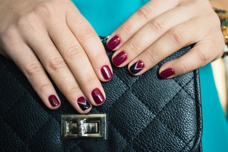 Female nails with red nail polish and a beautiful black handbagの写真素材