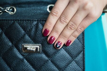 Female nails with red nail polish and a beautiful black handbagの写真素材