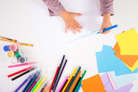 little girl drawing with colored pencils on paperの写真素材