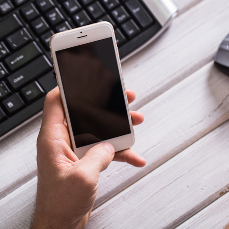 Hands of businessman using a mobile phone and keyboardの写真素材