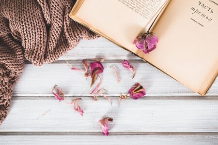 Dried flowers with a book and a warm scarf on wooden backgroundの写真素材