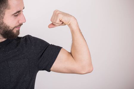 Portrait of a funny man showing his muscles over gray backgroundの写真素材