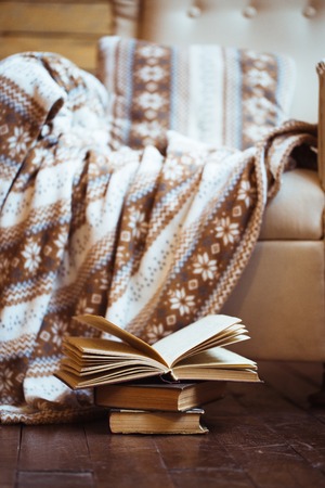 Stack of books with warm plaid on chairの写真素材