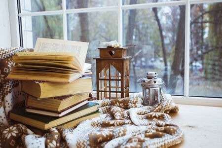 Stack of books with a warm blanket on a windowsillの写真素材