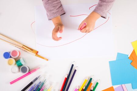 little girl drawing with colored pencils on paperの写真素材