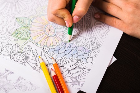 Girl paints a coloring book for adults with crayonsの写真素材