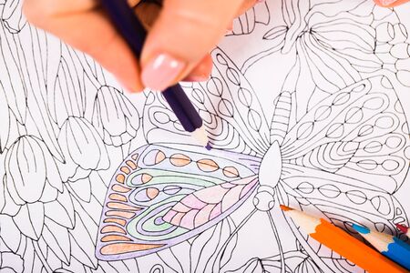 Girl paints a coloring book for adults with crayonsの写真素材