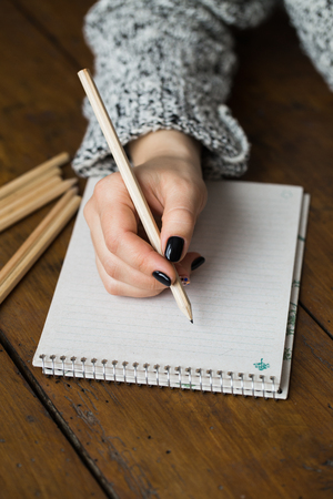 A woman with a beautiful manicure draws in a notebookの写真素材
