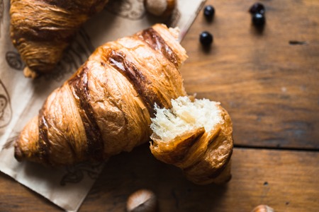 Tasty buttery croissants on old wooden table.の写真素材