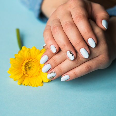 Girl with blue manicure holds a yellow flowerの写真素材