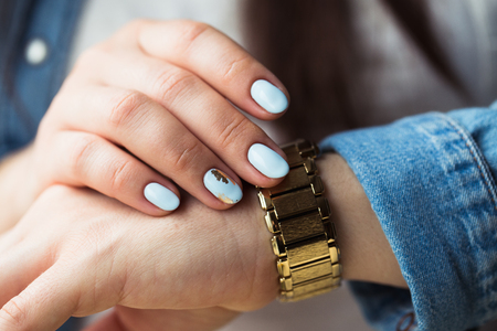 Stylish girl with a blue manicure and a golden clock. Fashion, lifestyle, beauty, clothing.の写真素材