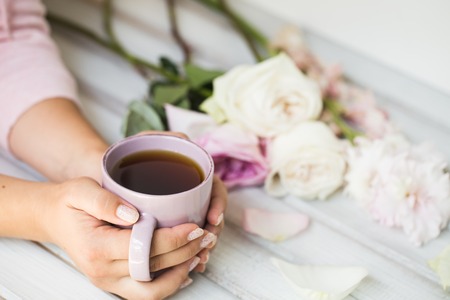 woman holding hot cup of tea on a wooden background. Morning, drink, breakの写真素材