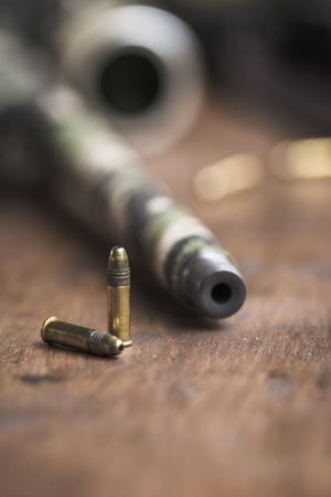 Small caliber 22 long rifle with an optical sight and cartridges in camouflage tape