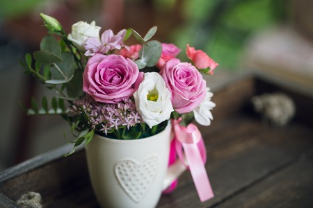 Beautiful flowers in cup on wooden backgroundの写真素材
