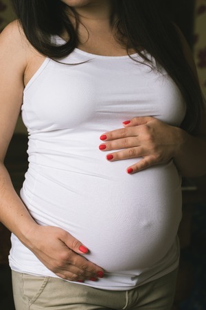 Young pregnant woman holds her hands.の写真素材
