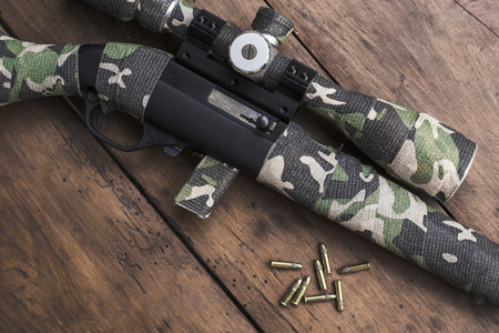 Small caliber 22 long rifle with an optical sight and cartridges in camouflage tape