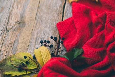 Autumn leaves and knitted sweater on a wooden backgroundの写真素材