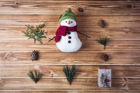 Christmas background decorations on fir tree branches with gift boxes and snowman cookie on wooden tableの写真素材