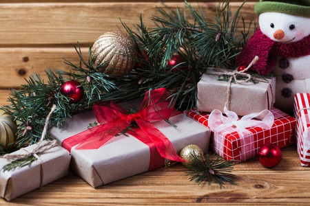 Christmas background decorations on fir tree branches with gift boxes and snowman cookie on wooden tableの写真素材