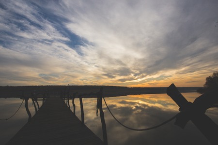 Perspective view of a wooden pier on a river at sunsetの写真素材