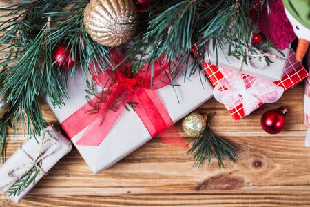 Christmas background decorations on fir tree branches with gift boxes and snowman cookie on wooden tableの写真素材