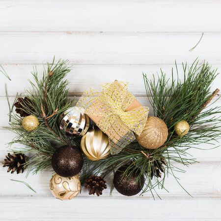 Christmas gift box with ribbon bow and branch christmas tree and ball toy and cone on white wooden vintage backgroundの写真素材