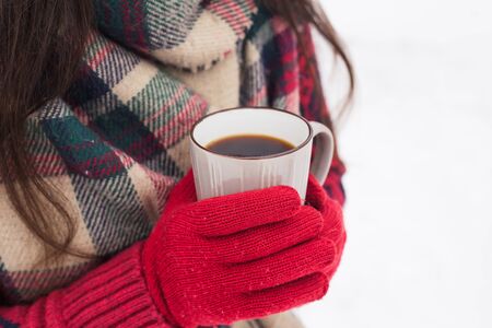 Beautiful happy smiling woman with a cup in the winter on the street