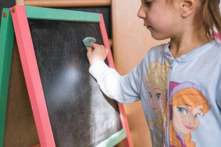 Little girl drawing on black boardの写真素材