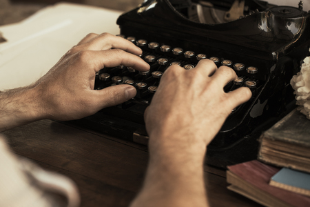 Young man's hands typing on an antique vintage typewriterの写真素材