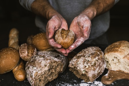 Baker man holding a rustic organic loaf of bread in his handsの写真素材