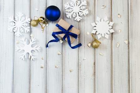 Christmas gift box with ribbon bow and ball toy on white wooden backgroundの写真素材
