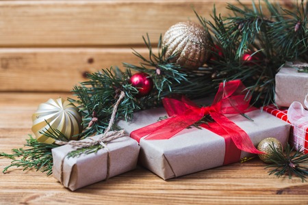 Christmas decorations on fir tree branches with gift boxes and snowman cookie on wooden tableの写真素材