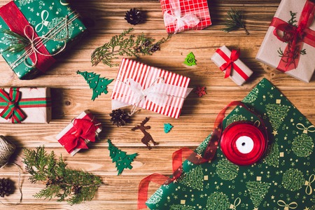 Christmas holiday gift box on decorated festive table with pine cones on wooden backgroundの写真素材