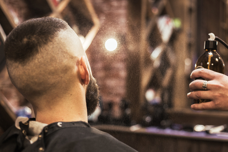 Bearded barber splashes after cutting from an aerosol can on the client's skinの写真素材