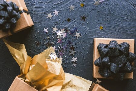 Christmas gifts with a gold and black bow on a black background. Open gift with stars.の写真素材