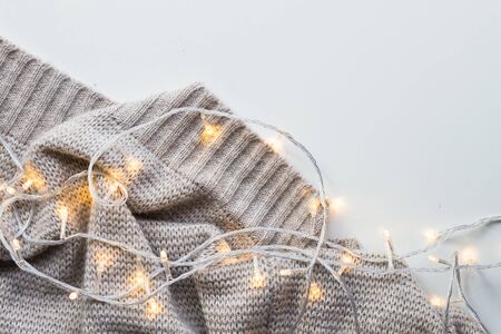 Knitted plaid with a garland on a white background. Christmas backround.の写真素材