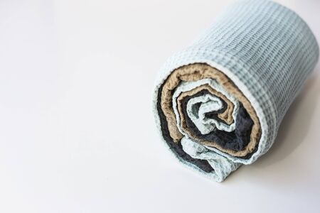 Pile of dull-colored waffle linen cotton napkins towels on white background. Different colors. Roll of kitchen towelsの写真素材