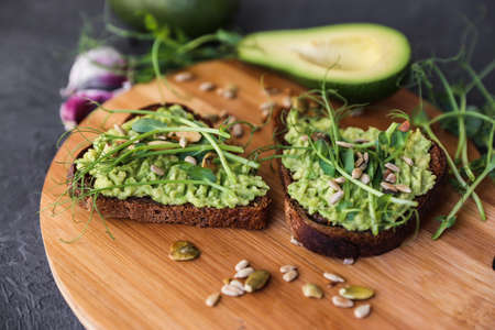 Detox breakfast. Freshly cooked whole grain toasts with avocado spread and microgreen sprouts, close upの写真素材