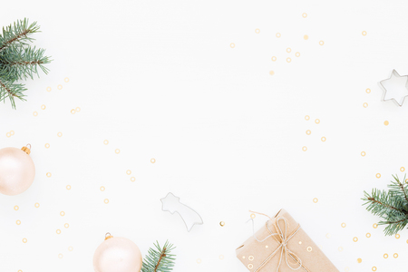 Minimal styled Christmas background with gift box, blush baubles, fir branches and baking molds on white. Holiday flat lay, top view.の写真素材